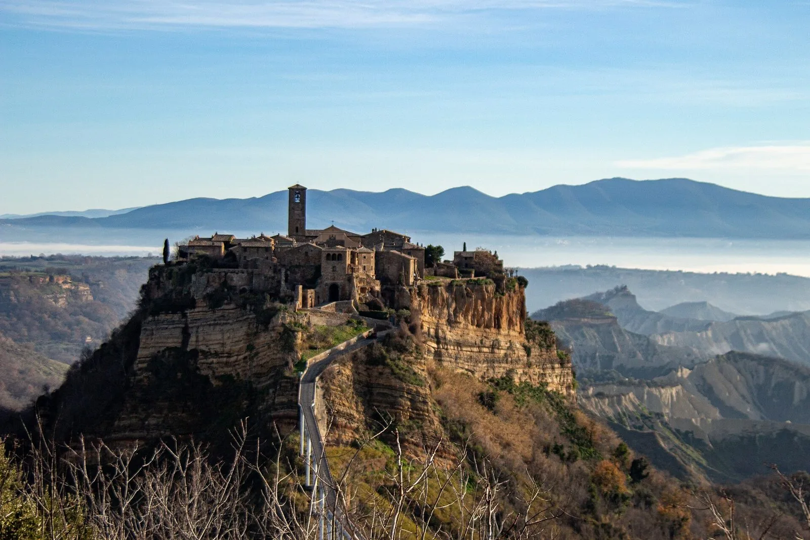 Civita di Bagnoregio sulla sua rupe di tufo, con la valle dei calanchi e la foschia sulla pianura sullo sfondo