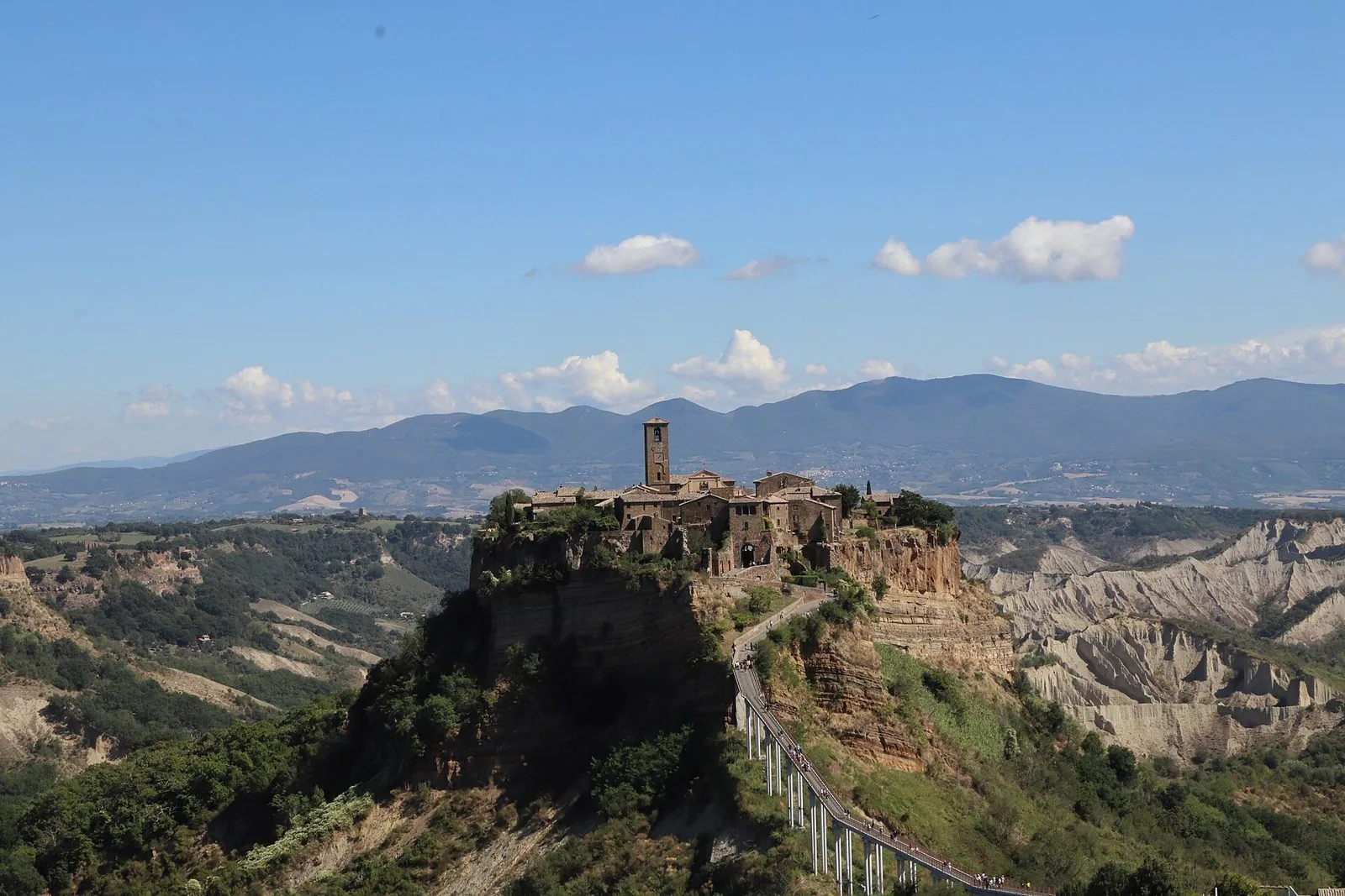 Civita di Bagnoregio sullo sperone di tufo con il ponte pedonale e i calanchi, vista dal belvedere